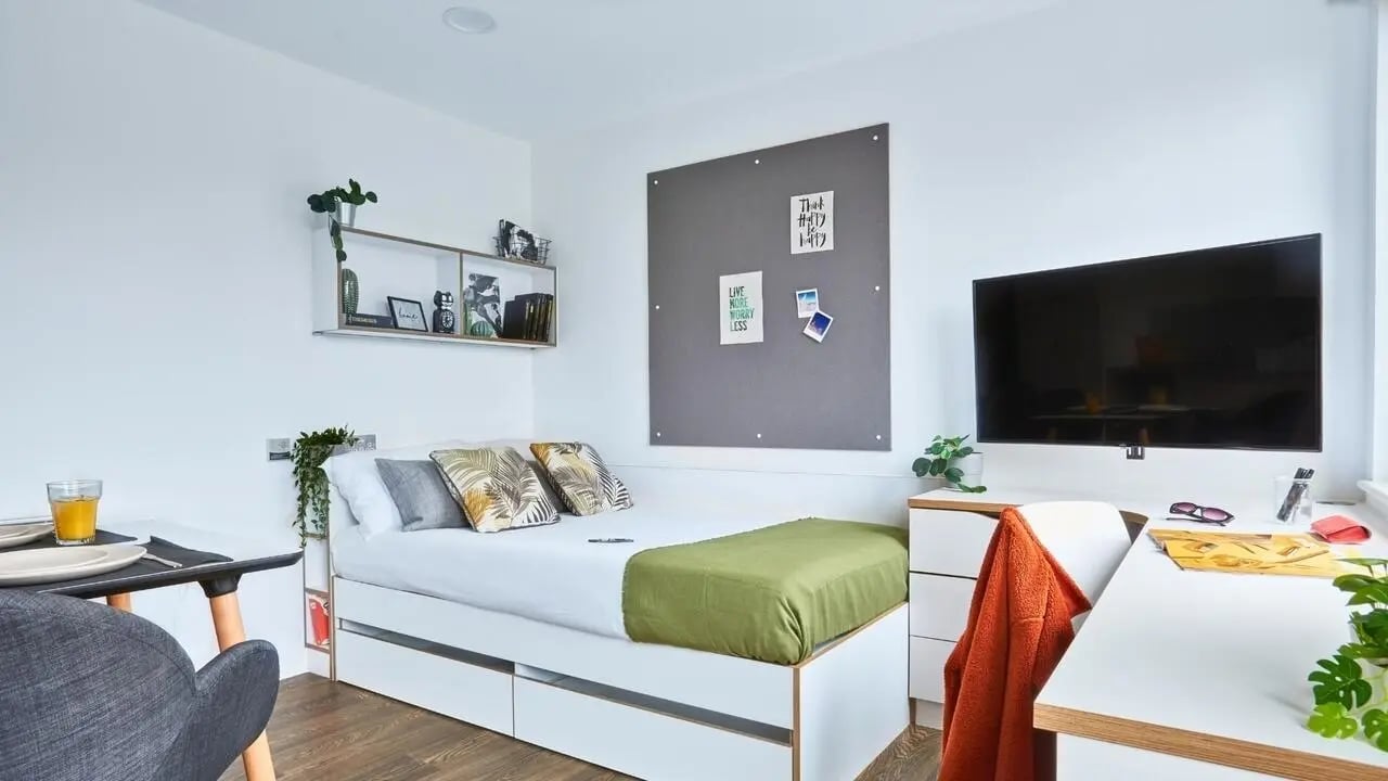 Bed with green throw desk TV and chair bedroom at 41 Castle Street in Leicester Student Accommodation