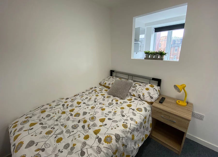 Bed with floral duvet nightstand yellow lamp Bedroom at Renaissance House in Leicester Student Accommodation
