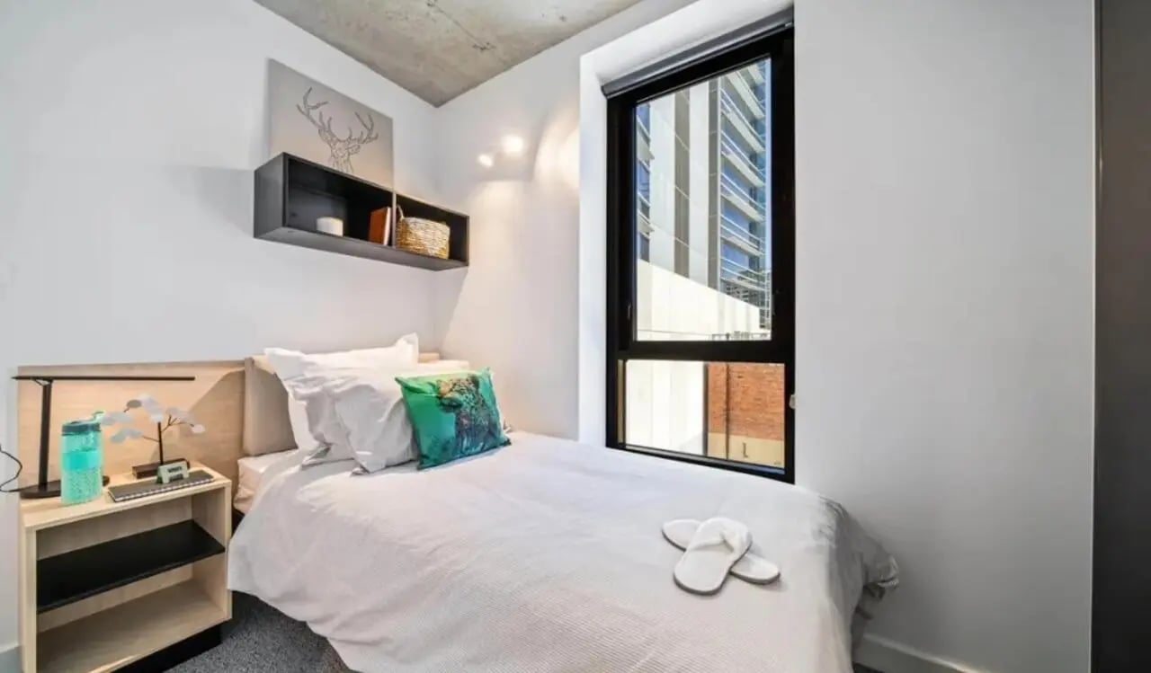 Bed pillows shelf lamp water bottle slippers bedroom at Perth Central in Perth Student Accommodation