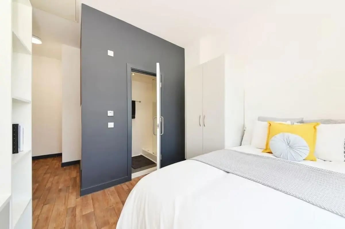 Bed wardrobe pillows and open bathroom door bedroom at Plymouth Cross House in Plymouth Student Accommodation