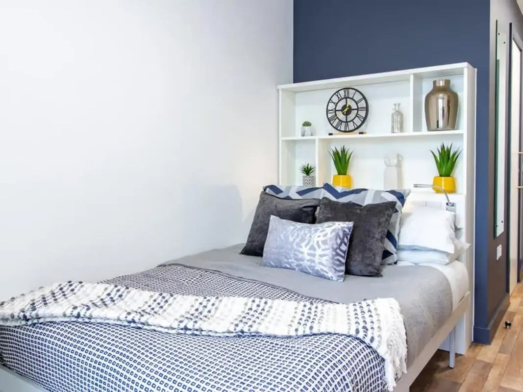 Bed with pillows and headboard bookshelf bedroom at Plymouth Cross House in Plymouth Student Accommodation
