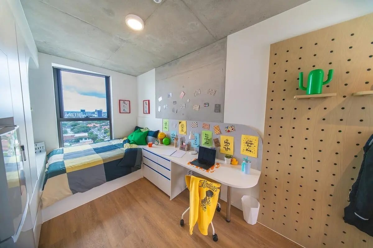 Bed desk with laptop and green cactus Bedroom study area at Scape Kensington in Sydney Student Accommodation