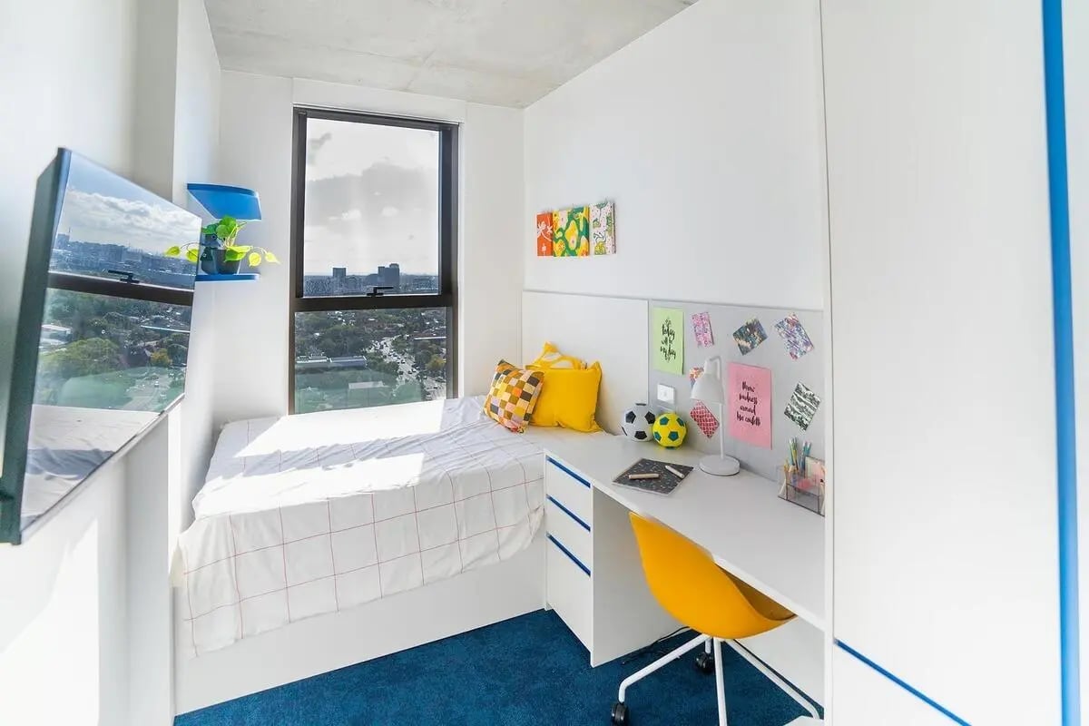 Bed desk yellow chair and TV bedroom at Scape Kensington in Sydney Student Accommodation