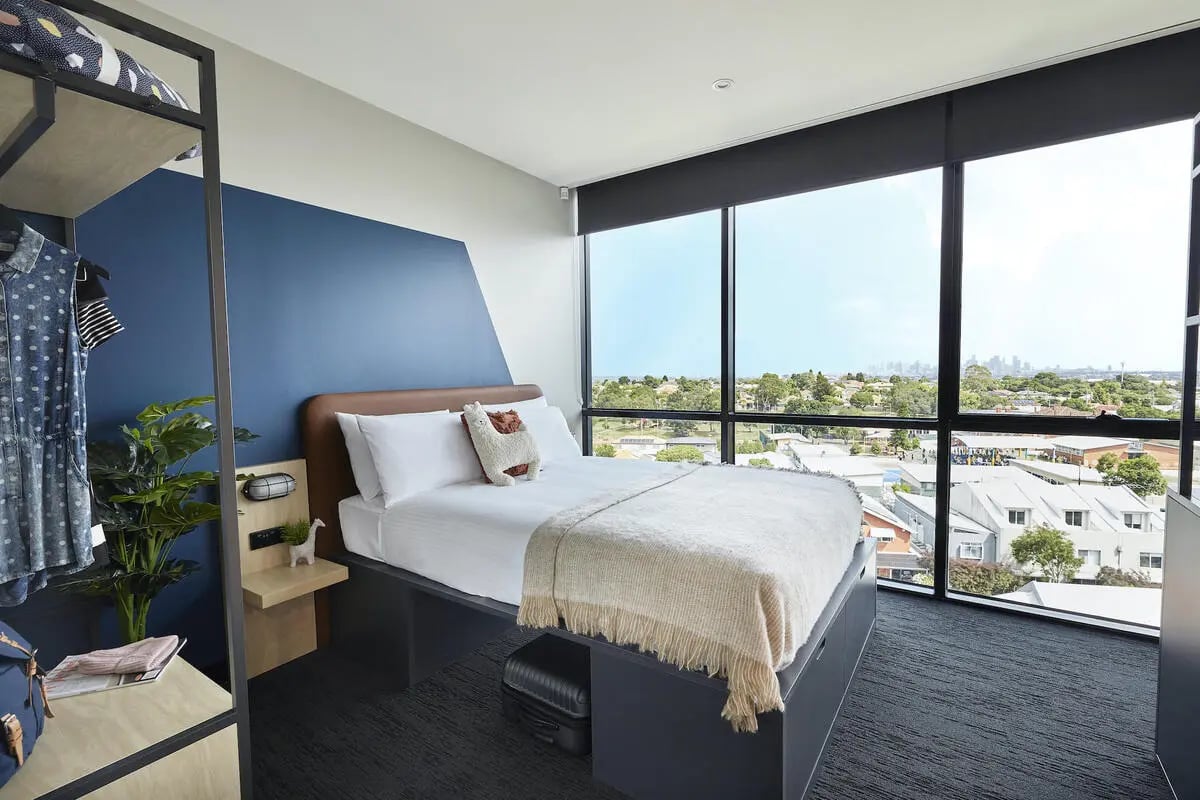 Bed plants luggage storage and city view bedroom at Campus Melbourne in Melbourne Student Accommodation