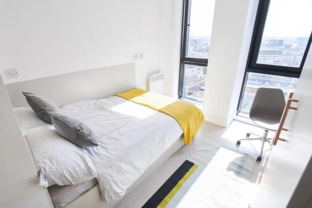 Bed with grey pillows yellow blanket desk chair bedroom at The Lantern in Liverpool Student Accommodation