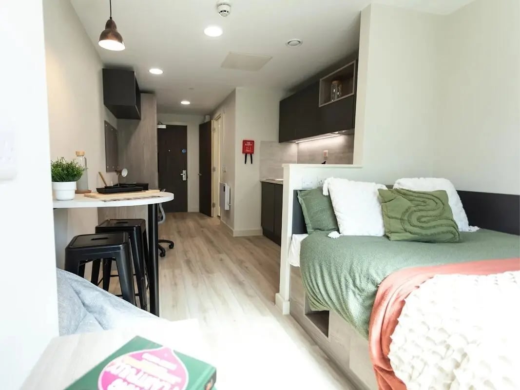 Bed with green bedding desk kitchen and stools bedroom at Stanley Studios - Portsmouth in Portsmouth Student Accommodation