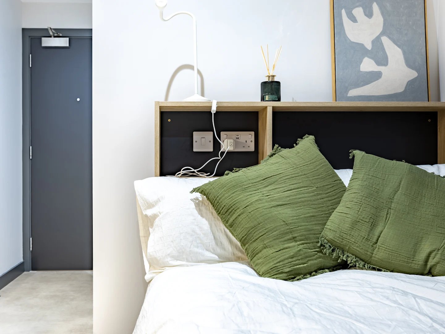 Bed with green pillows and wall art Bedroom at Biscuit Factory in Belfast Student Accommodation