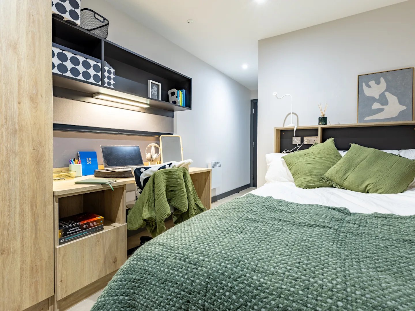 Bed desk laptop books green blankets bedroom at Biscuit Factory in Belfast Student Accommodation
