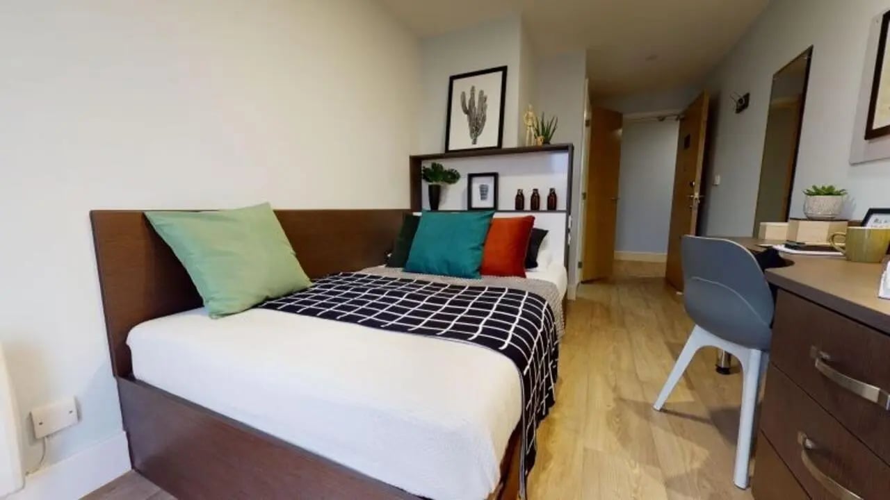 Bed with pillows desk with chair and plants bedroom at iQ Penworks House in Birmingham Student Accommodation