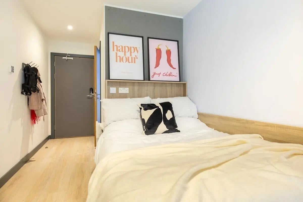Bed with pillows art and coats bedroom at Curraheen Point in Cork Student Accommodation