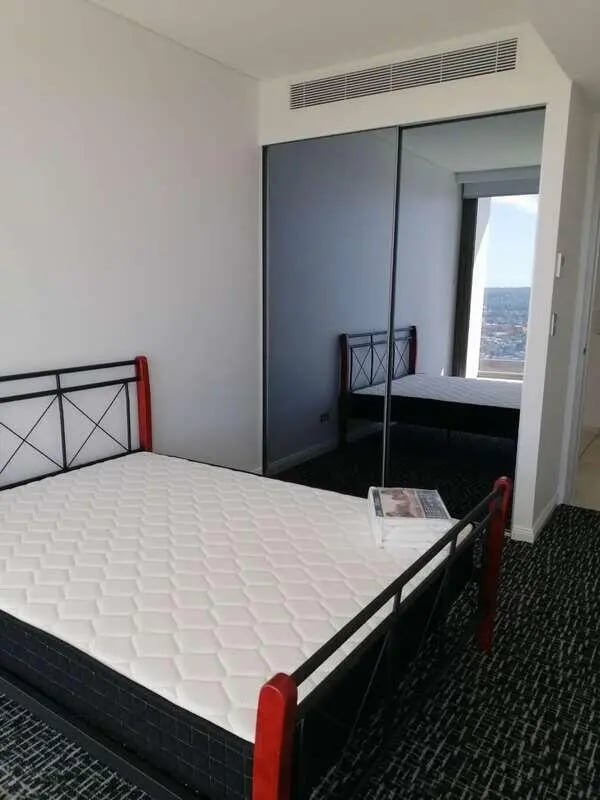 Bed with white mattress and mirrored wardrobe bedroom at Belong Macquarie in Sydney Student Accommodation