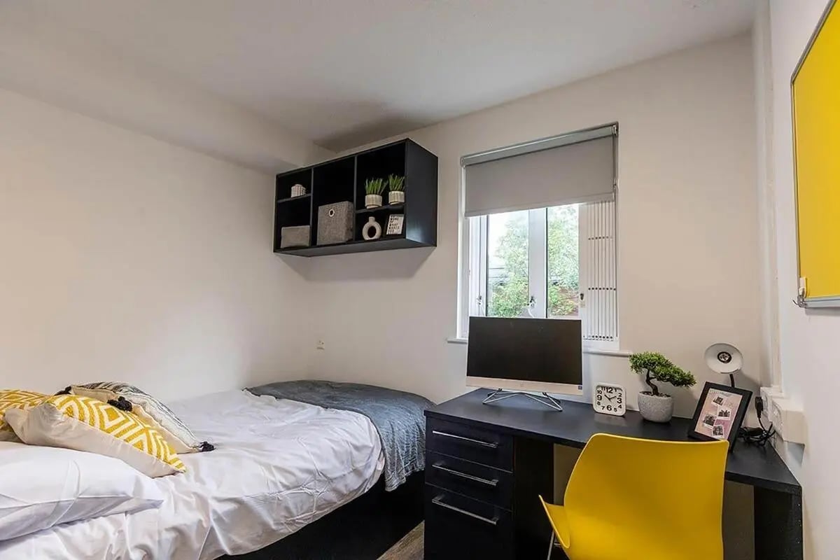 Bed desk shelves with decor and yellow chair bedroom at Woodhouse Flats in Leeds Student Accommodation
