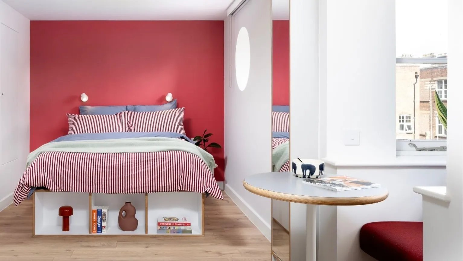 Bed with red striped duvet table with magazines bedroom interior at Scape Kings Cross in London Student Accommodation