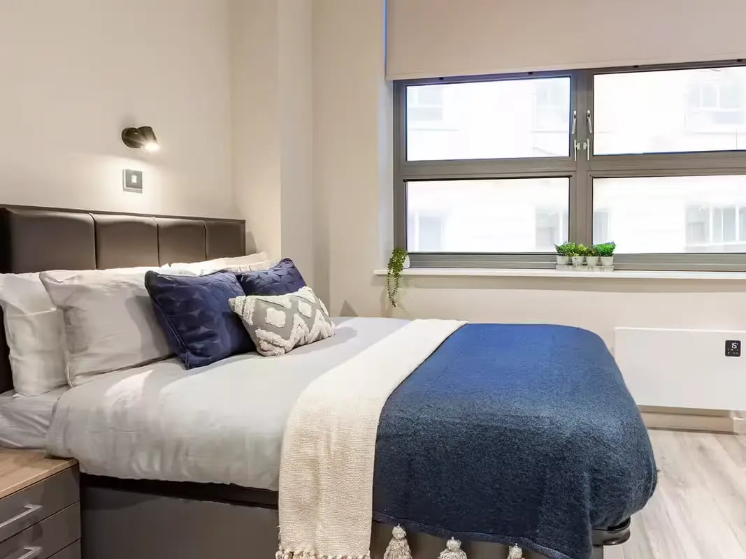 Bed pillows blankets window wall heater bedroom at Grosvenor House in London Student Accommodation
