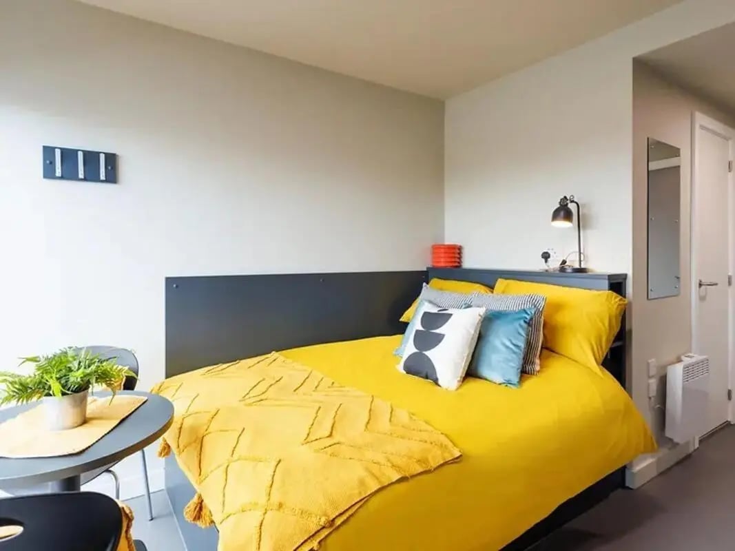 Yellow bedding pillows modern lamp side table bedroom at Element Manchester in Manchester Student Accommodation