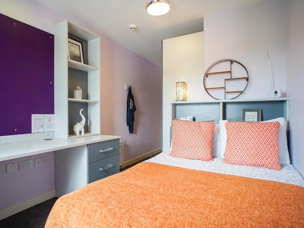 Bed with orange quilt desk and shelves bedroom at Beaverbank Place in Edinburgh Student Accommodation