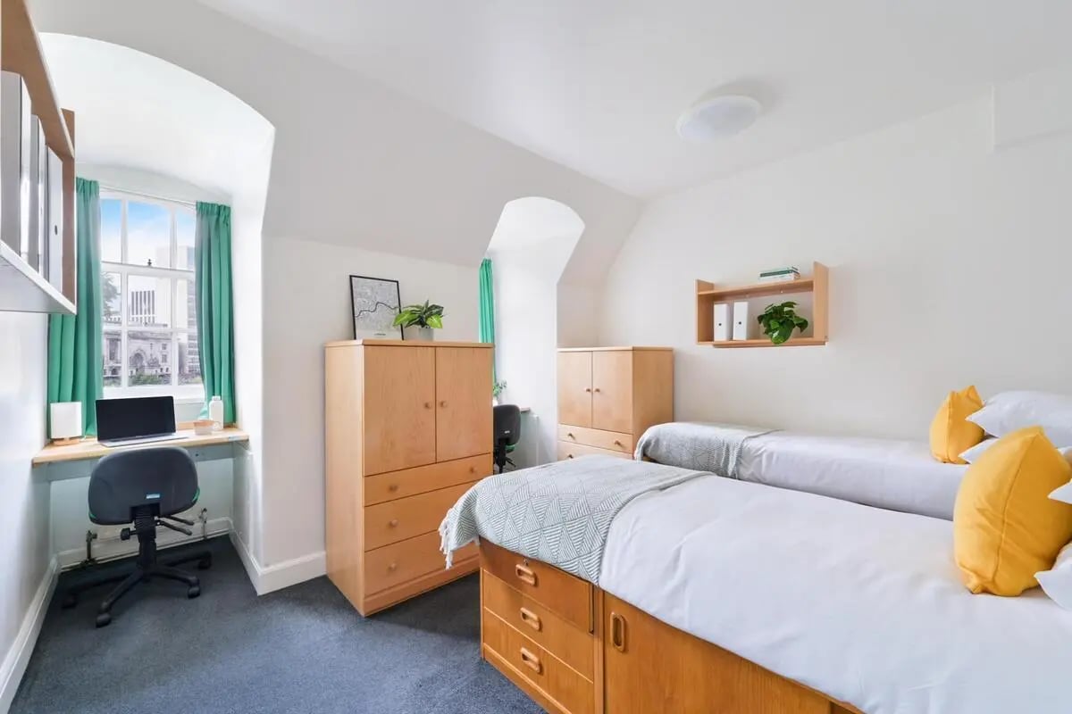 Two beds desk drawers and a laptop Bedroom at AXO Waterloo in London Student Accommodation