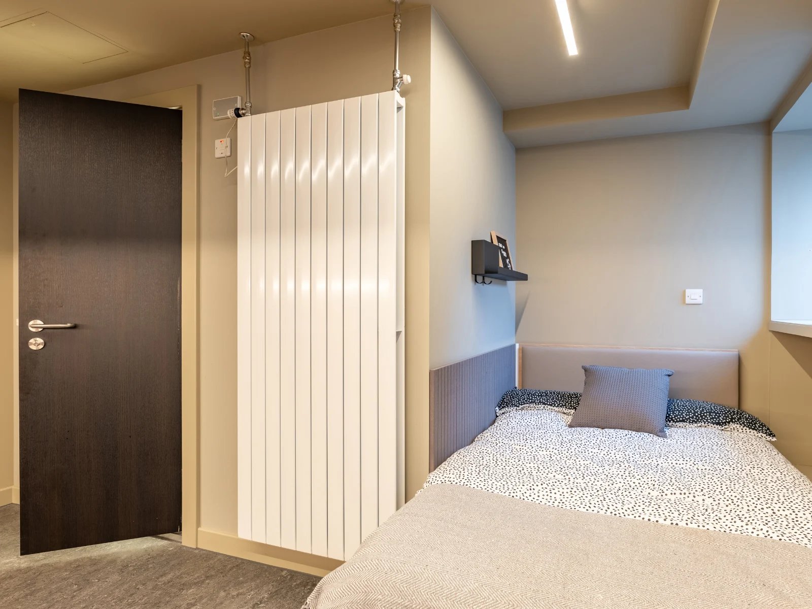 Dark wood door white radiator and bed bedroom at Potterrow in Edinburgh Student Accommodation
