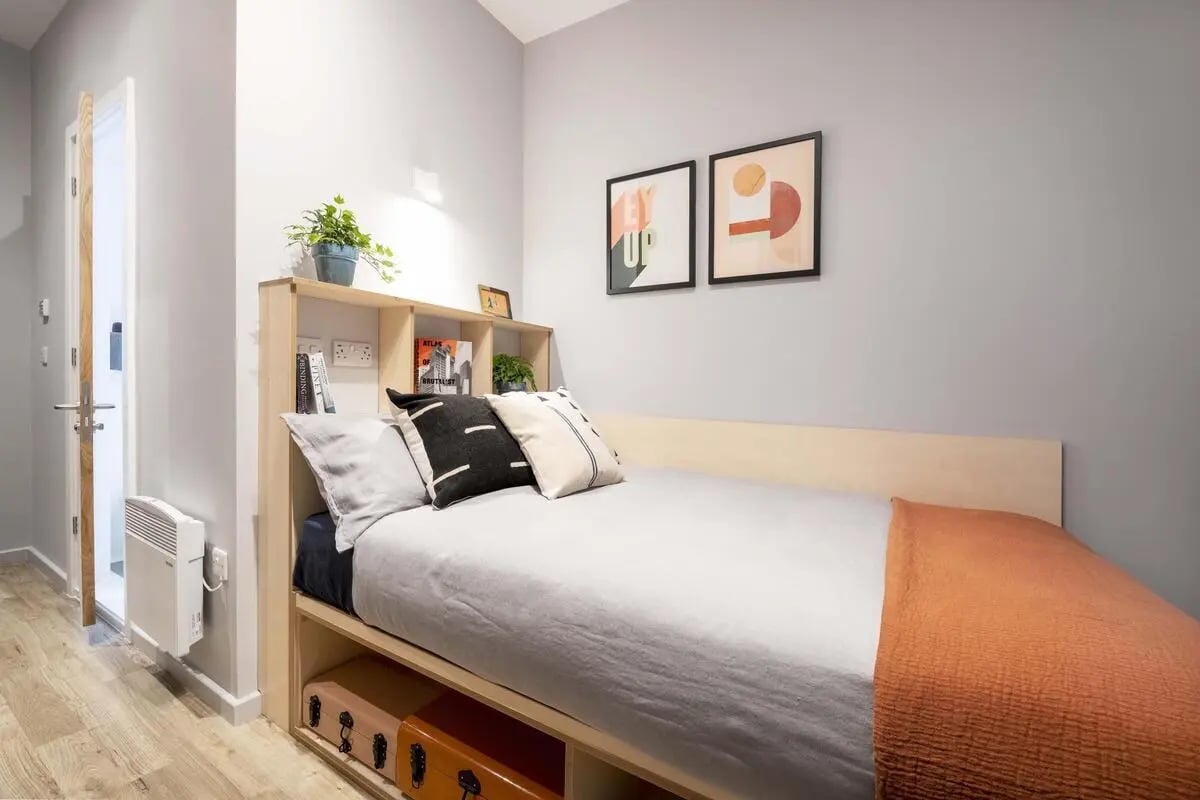 Bed shelves pillows heater and door bedroom at Hillside House Sheffield in Sheffield Student Accommodation