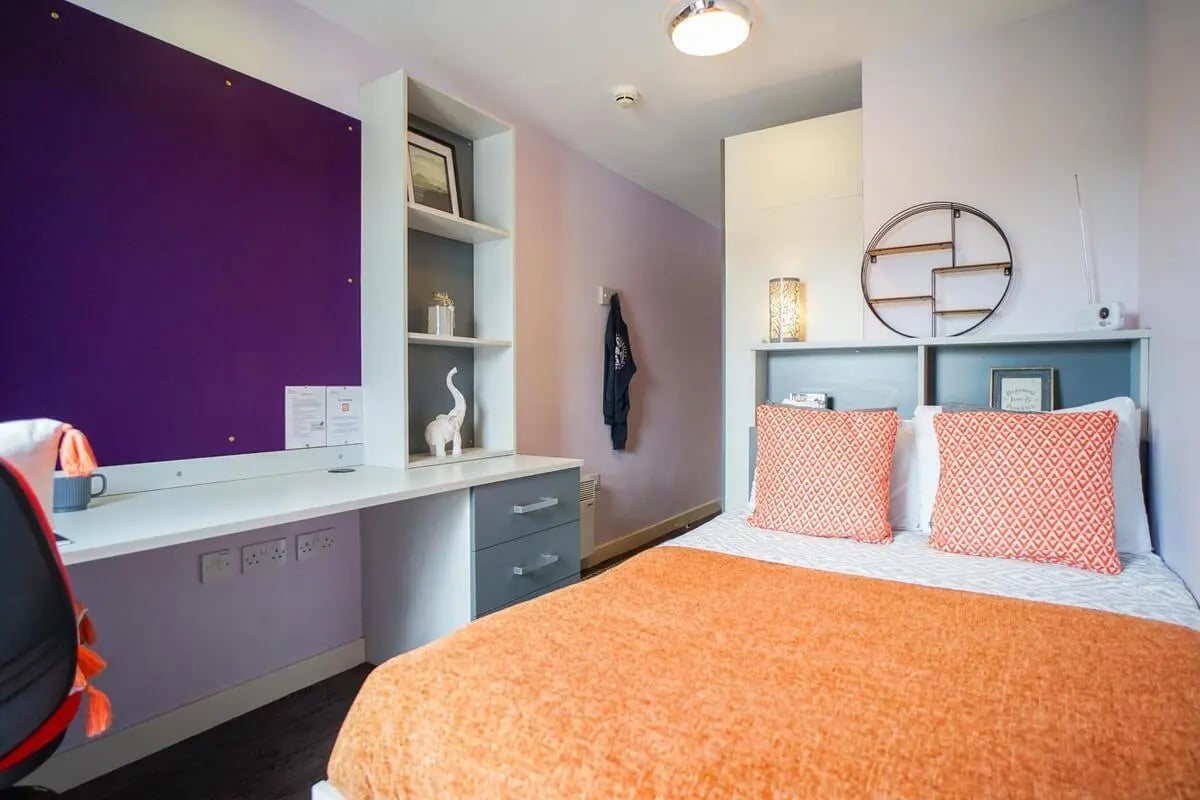 Desk bed purple board shelving orange bedding bedroom at Beaverbank Place in Edinburgh Student Accommodation