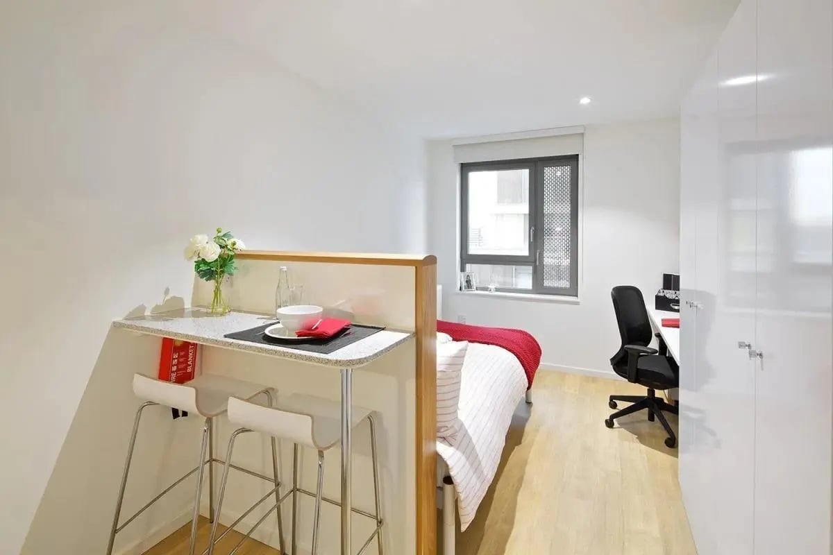Bar with stools bed desk chair bedroom study area at Wood Lane Studios in London Student Accommodation