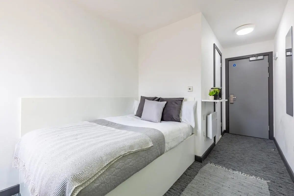 Bed pillows radiator door carpeted floor bedroom at Glassworks - Liverpool in Liverpool Student Accommodation