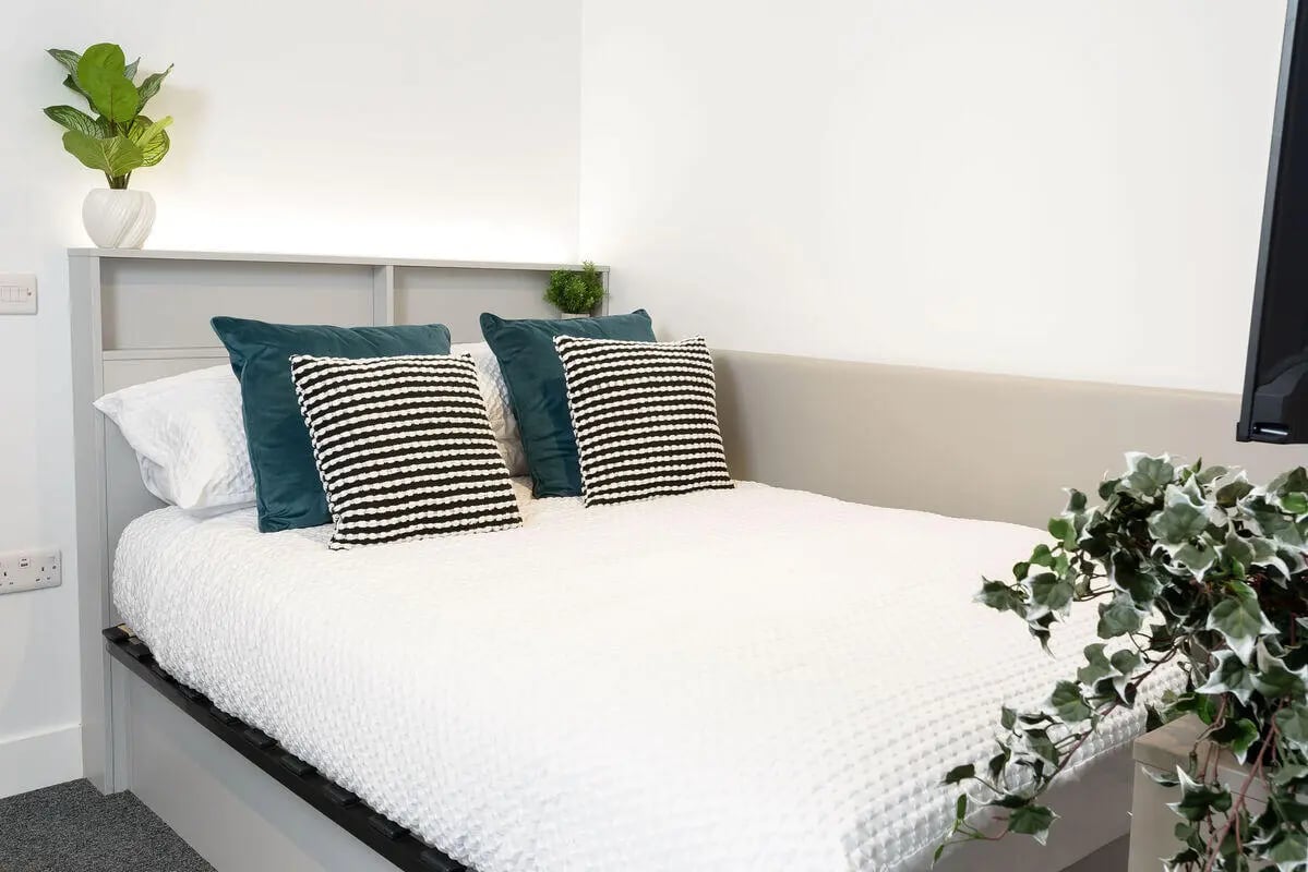 Bed with white bedding pillows and plants Bedroom at True Sheffield in Sheffield Student Accommodation