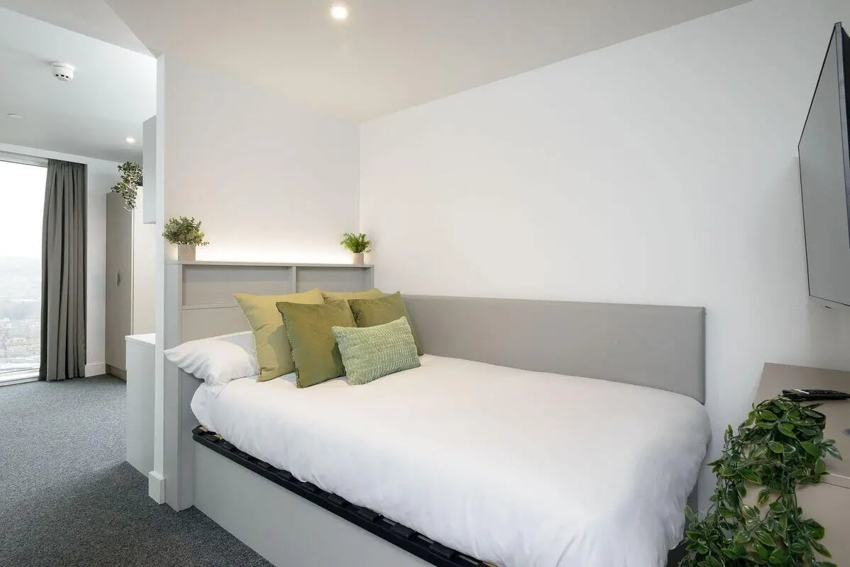 White bed with green pillows study area bedroom at True Sheffield in Sheffield Student Accommodation
