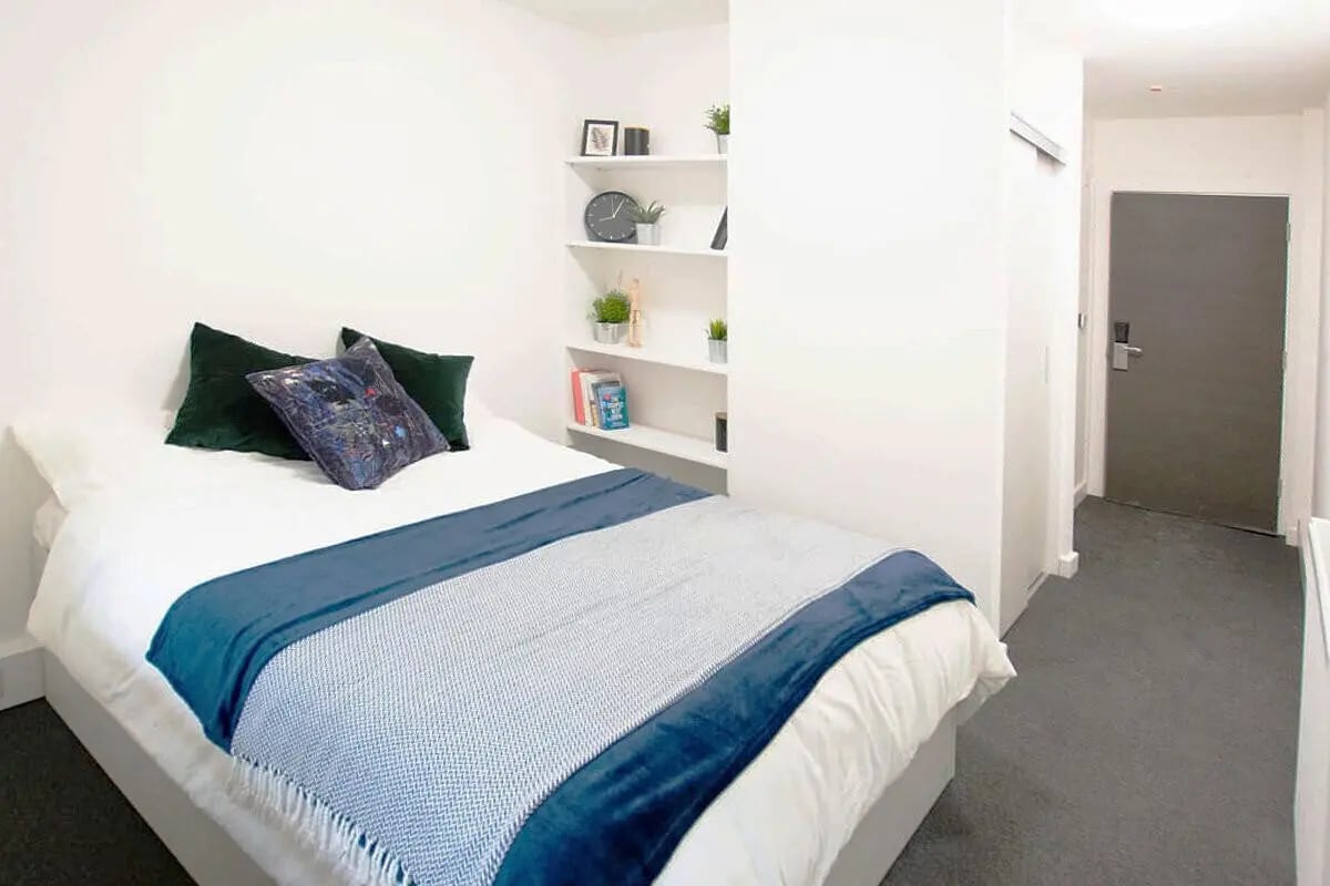Bed with blue throw and green pillows bedroom at The Paper Works in Sheffield Student Accommodation