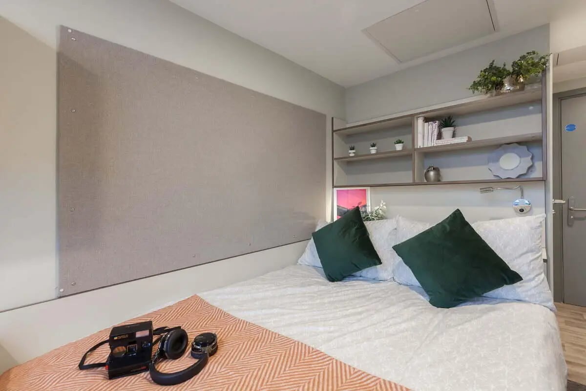 Bed with pillows camera headphones shelves bedroom at LIV Student Sheffield in Sheffield Student Accommodation