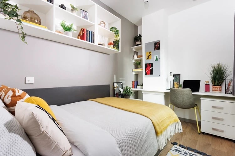 Bed with yellow throw desk with laptop shelves Bedroom at Hayloft Point in London Student Accommodation
