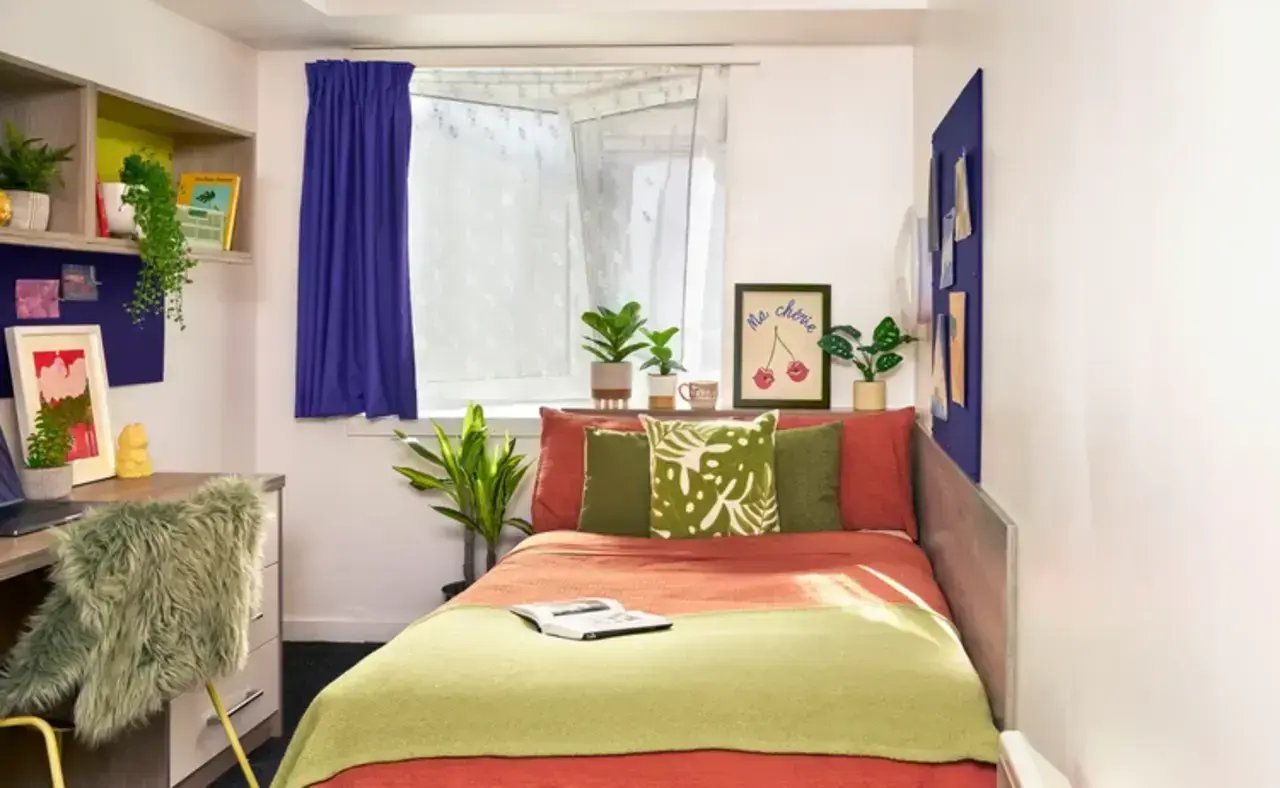 Bed with desk and plants Student bedroom at Queen's Park House in Coventry Student Accommodation