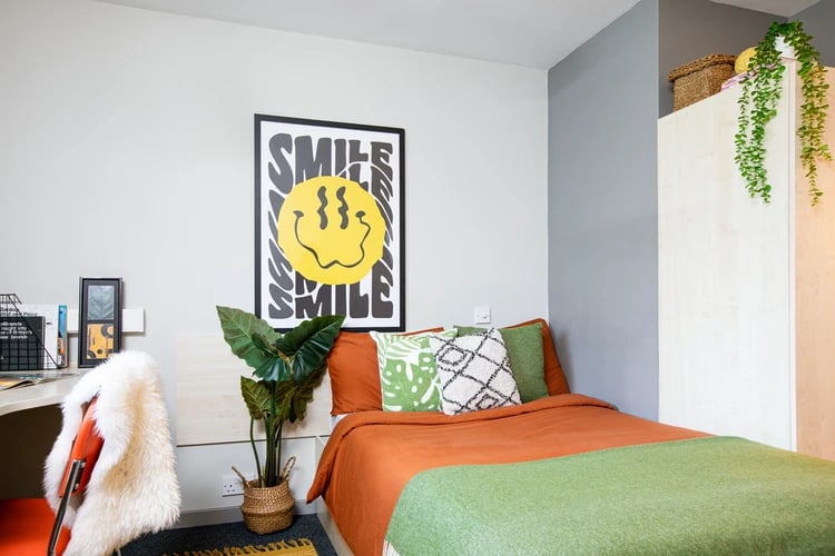 Bed with orange blanket and green throw bedroom at Blackfriars in Glasgow Student Accommodation