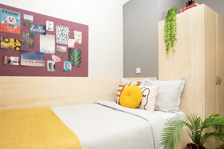 Bed with yellow blanket corkboard and wardrobe bedroom at Blackfriars in Glasgow Student Accommodation