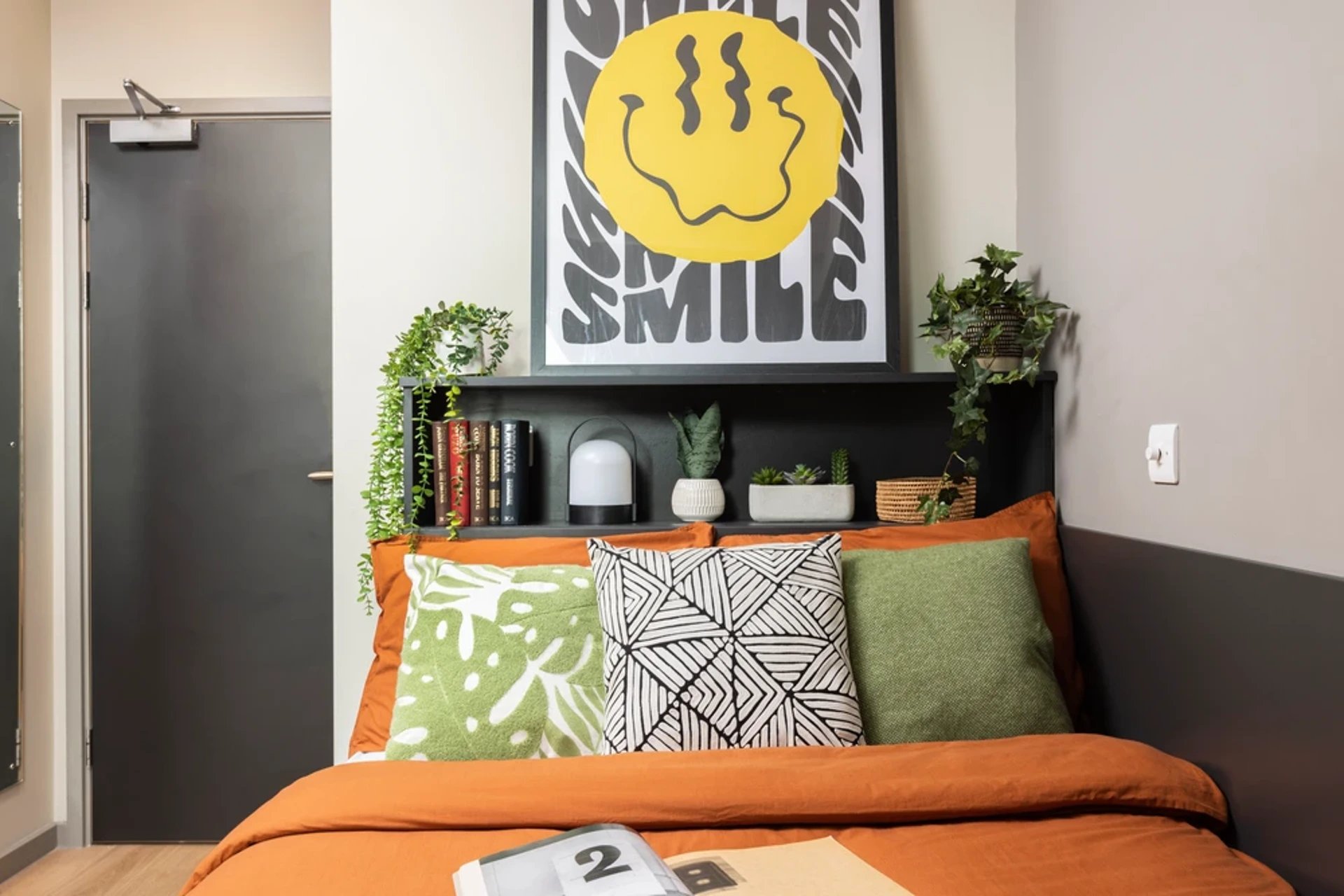 Bed with orange bedding and patterned pillows Bedroom at Arch View House in London Student Accommodation