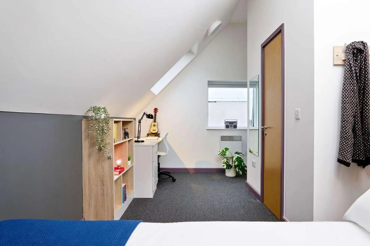 Bookshelf desk guitar plants door bedroom at Westwood Student Mews in Coventry Student Accommodation