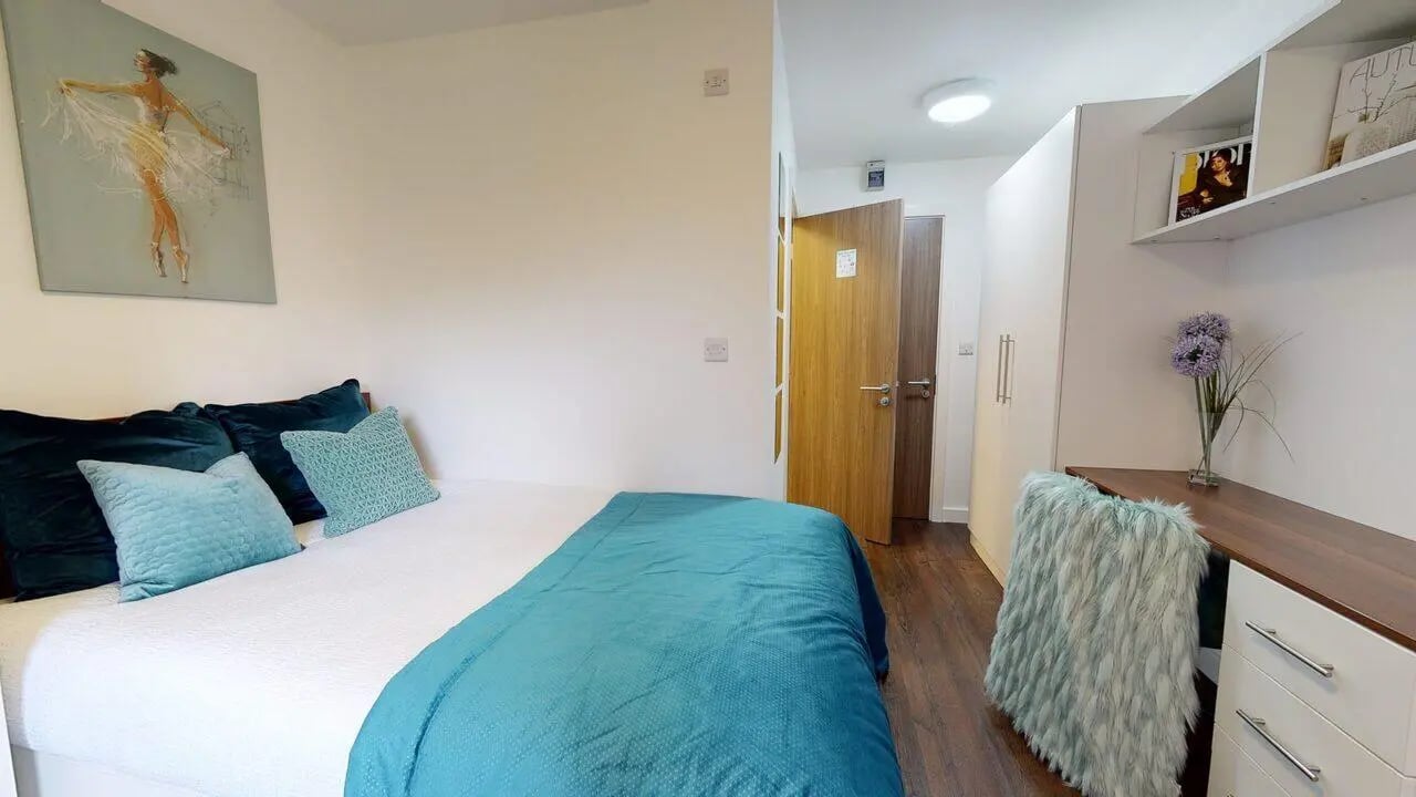 Bed with blue pillows desk with furry chair bedroom at Park House in Luton Student Accommodation