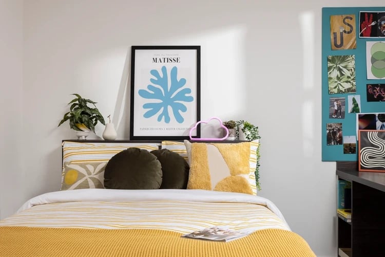 Bed with yellow blanket artwork and wall display Bedroom at Mill Point in Manchester Student Accommodation