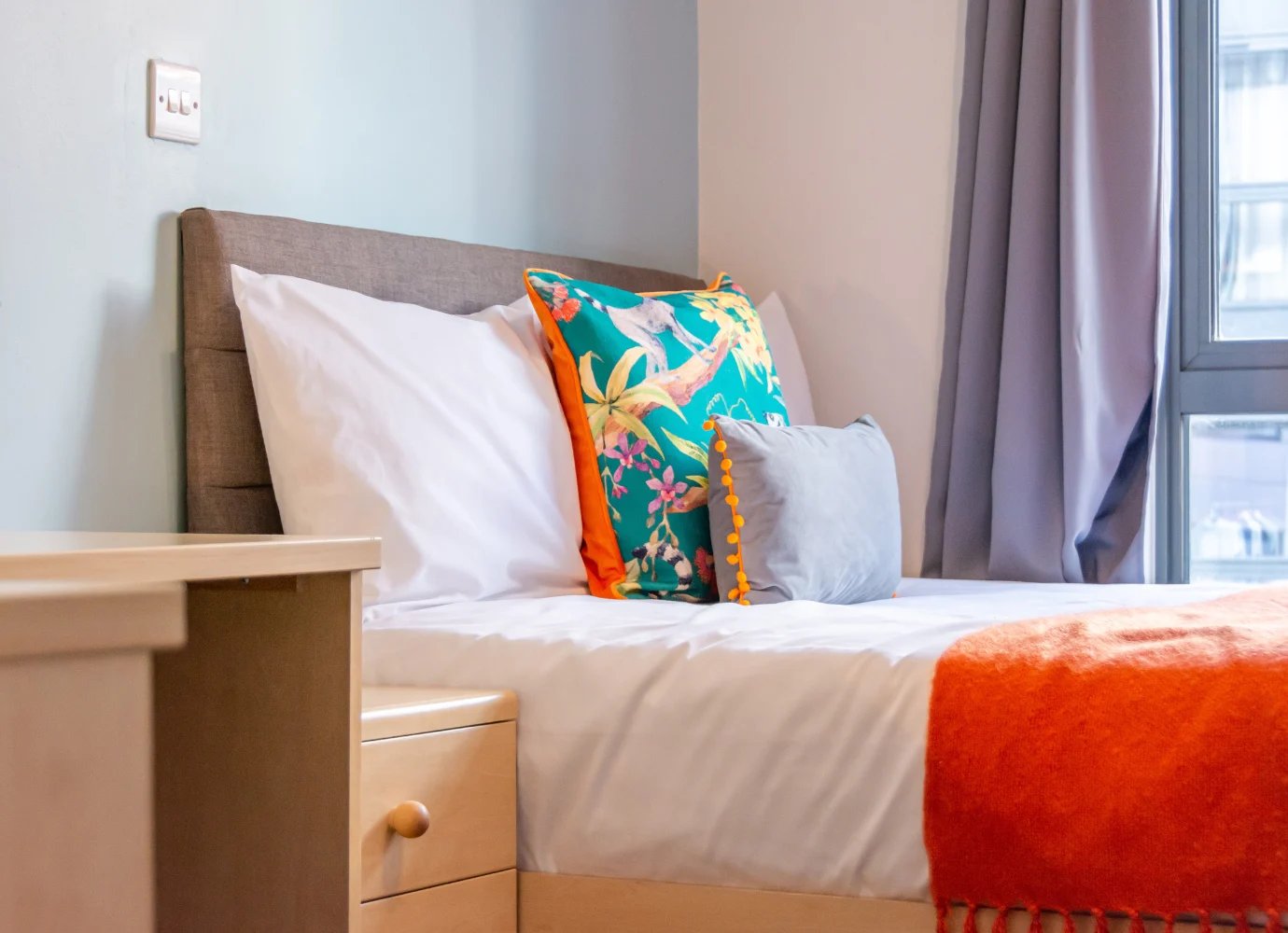 Bed with colorful pillows and orange throw bedroom at Iconinc The Triangle in Leeds Student Accommodation