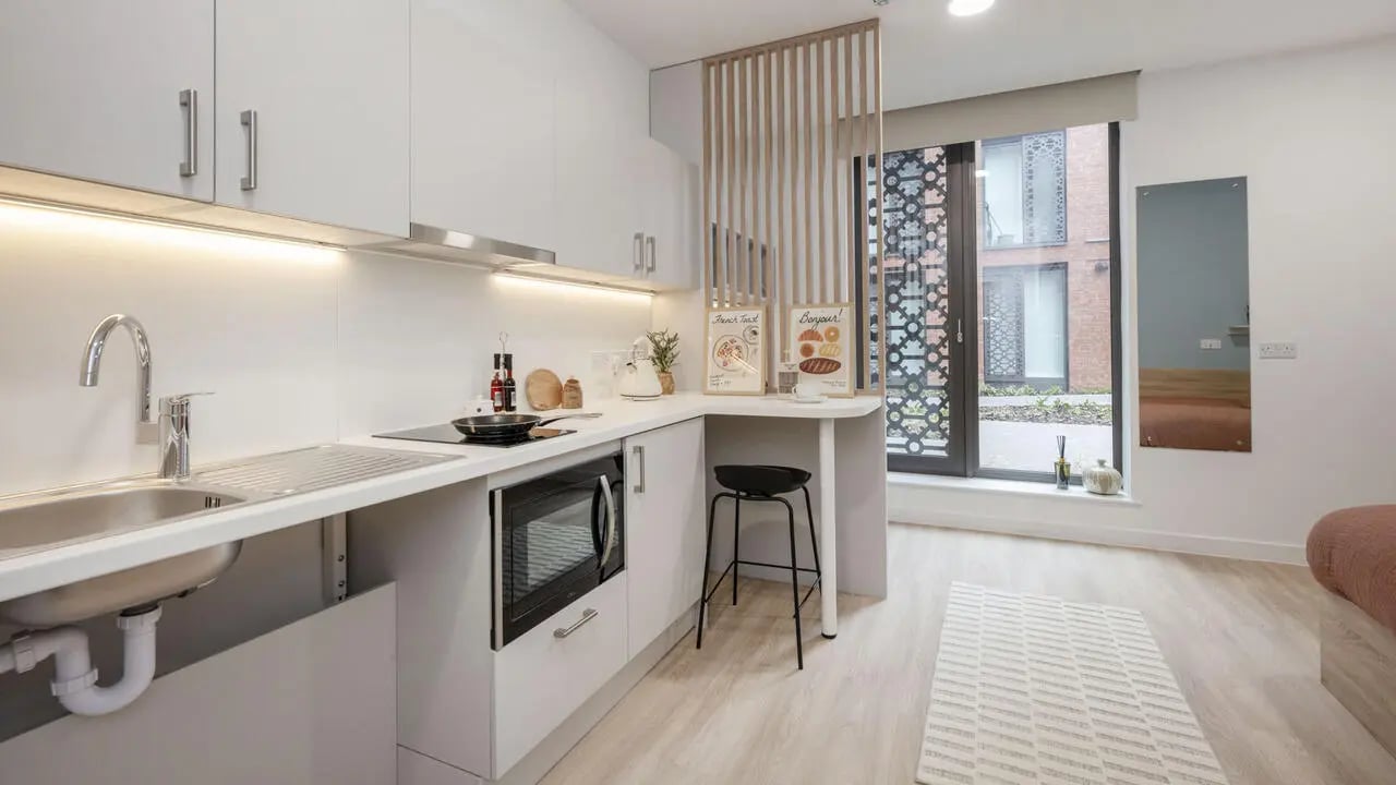 Modern kitchen with sink microwave oven and stool kitchen area at St Gabriels in Manchester Student Accommodation