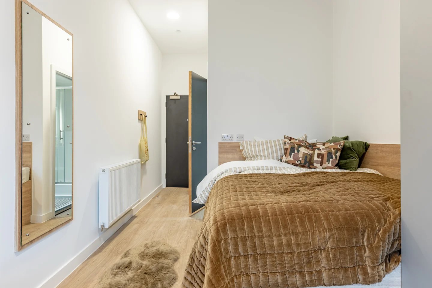 Bed with patterned pillows and fluffy rug bedroom at Beckton House in Nottingham Student Accommodation
