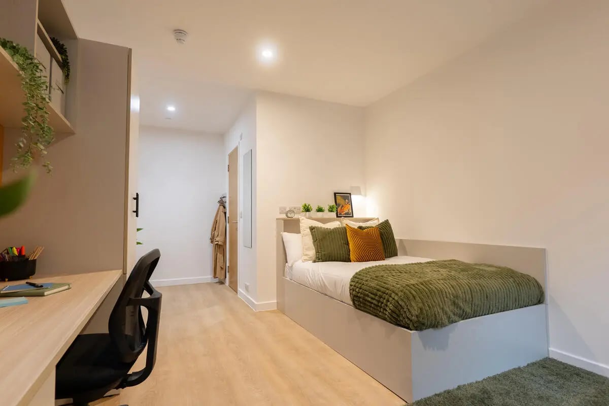 Desk chair bed with pillows and green blanket Bedroom at Telephone House in Dundee Student Accommodation