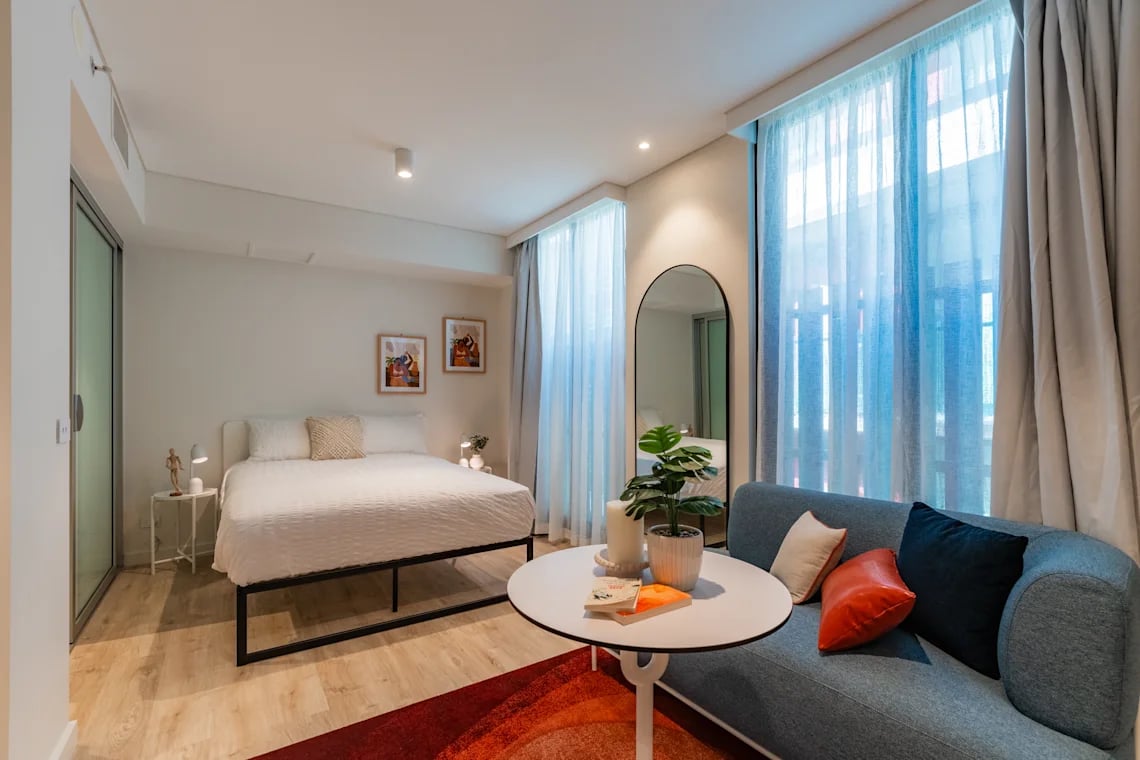 Bed sofa round table plants bedroom and living room at UKO Melbourne Central in Melbourne Student Accommodation