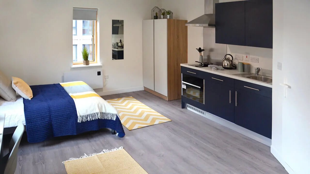 Bed kitchen area with sink and cabinets Studio apartment at Abode York in York Student Accommodation