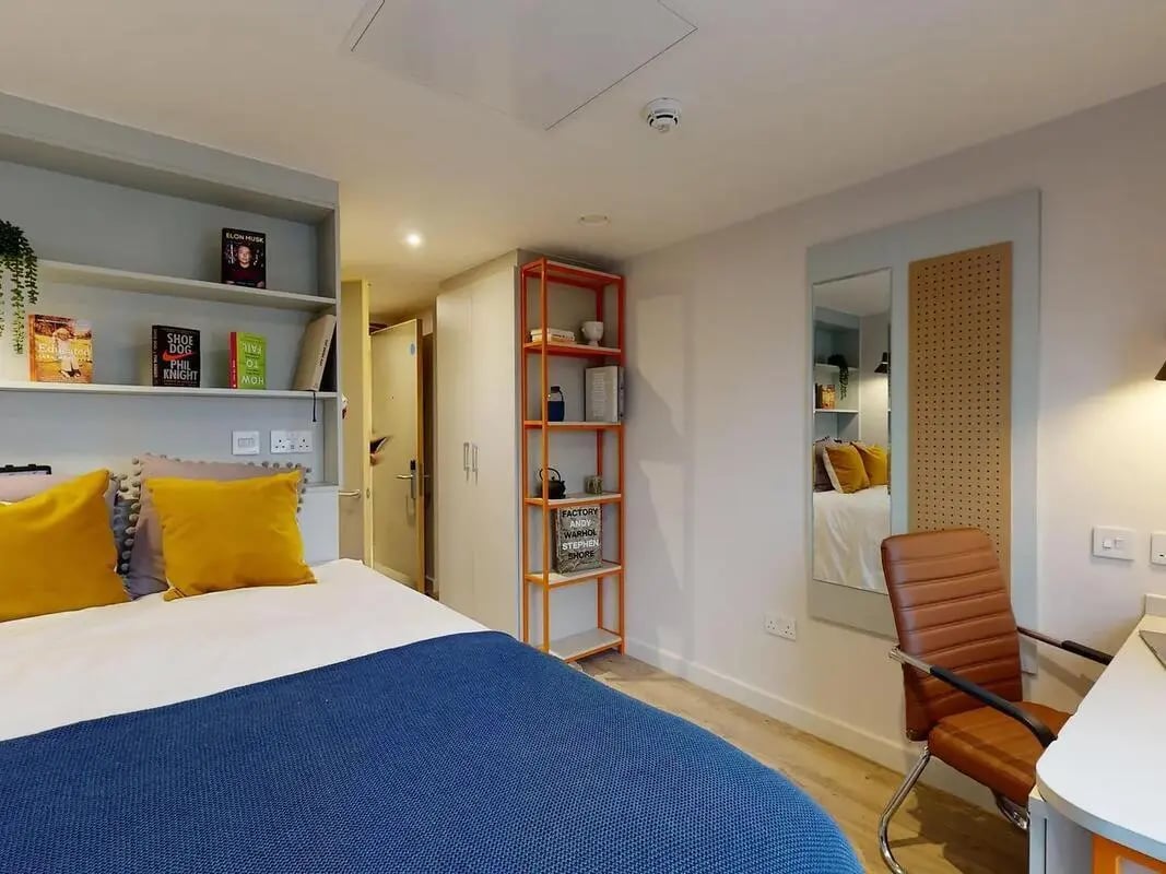 Bed with yellow pillows and blue throw bedroom at COSMOS in Sheffield Student Accommodation