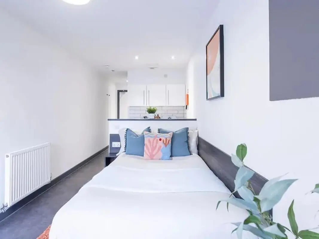 Bed with pillows radiator and kitchen area bedroom at The Foundry Newcastle in Newcastle Upon Tyne Student Accommodation