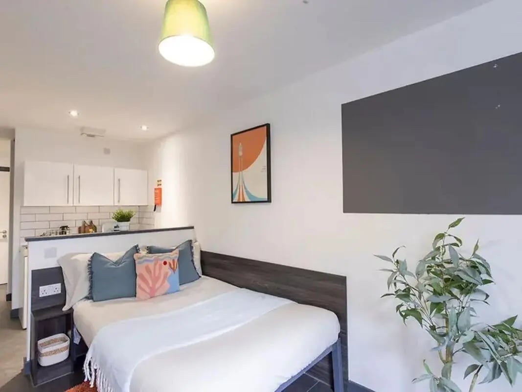 Bed with pillows and kitchen area studio at The Foundry Newcastle in Newcastle Upon Tyne Student Accommodation