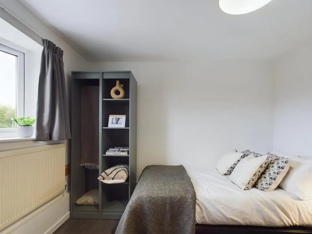 Bed with grey blanket and pillows shelving bedroom at 6 Bedroom House at 2, Flat 2, Windsor House, Clint Road West in Liverpool Student Accommodation