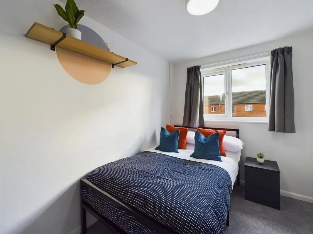 Bed with navy bedding blue pillows and nightstand bedroom at 6 Bedroom House at 13, Sage Road in Leicester Student Accommodation