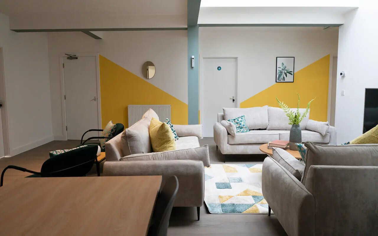 Sofa with yellow pillows geometric rug living room at 12 Bedroom House at Freya House, Thesiger Street in Lincoln Student Accommodation